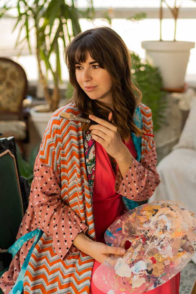 Portrait of a young beautiful girl wearing a white and colorful dress posing on grey background